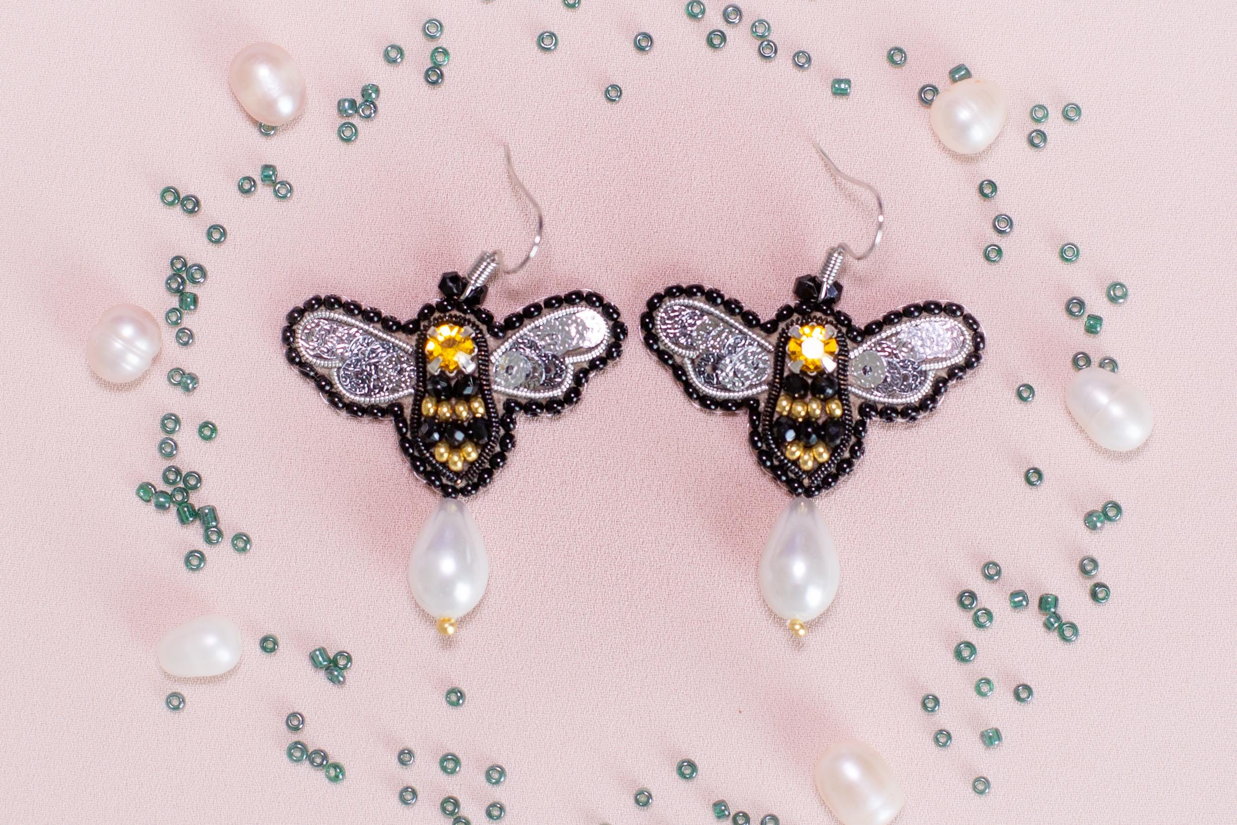 a pair of earrings with a bee on it